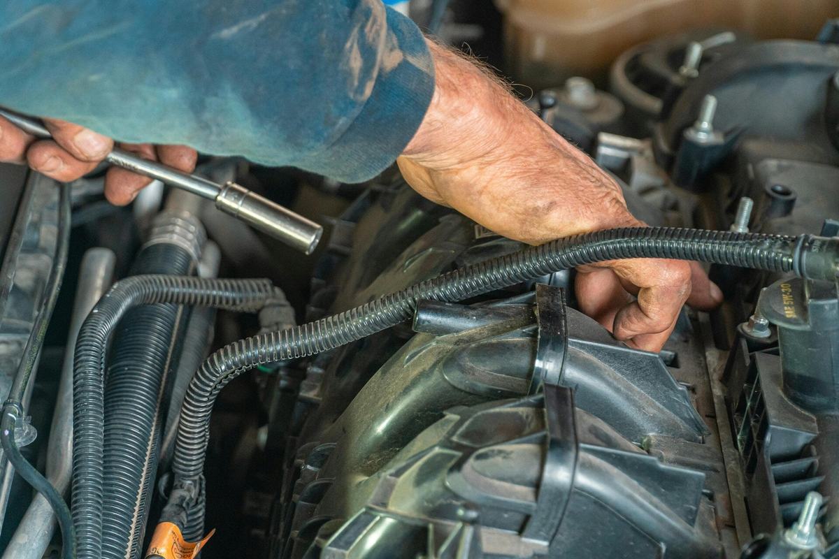 Mechanic's hands working on wiring and hoses in a diesel engine bay